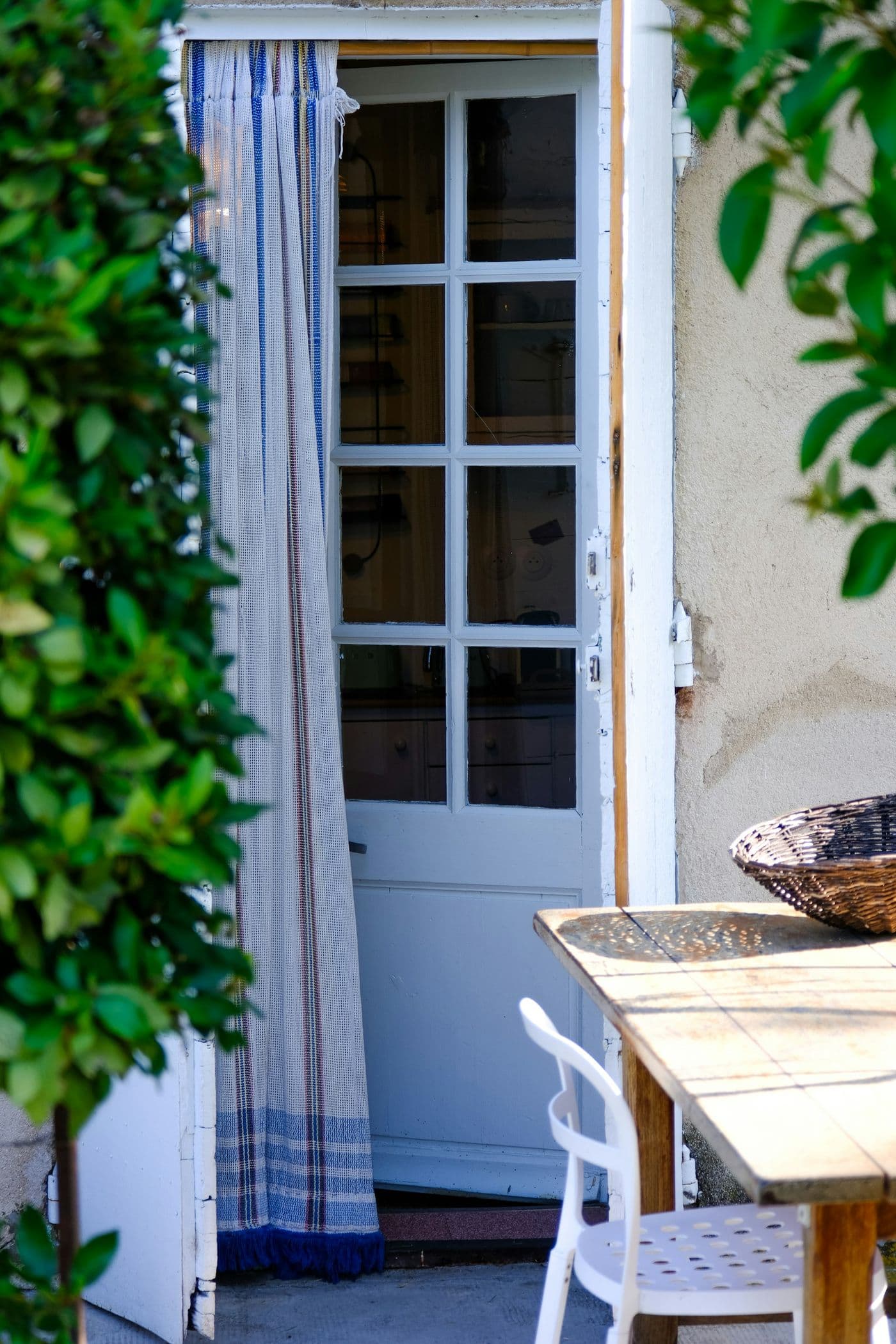 Terrasse ombragée d’une maison de vacances, table dressée près de la porte d’entrée